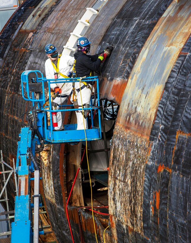 Shop 75 employees working in Dry Dock # 3 remove "SHT" Special Hull Treatment from the hull of the EX-USS Augusta SSN-710 (U.S. Navy photo by Wendy Hallmark)
