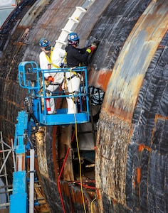 Shop 75 employees working in Dry Dock # 3 remove "SHT" Special Hull Treatment from the hull of the EX-USS Augusta SSN-710 (U.S. Navy photo by Wendy Hallmark)