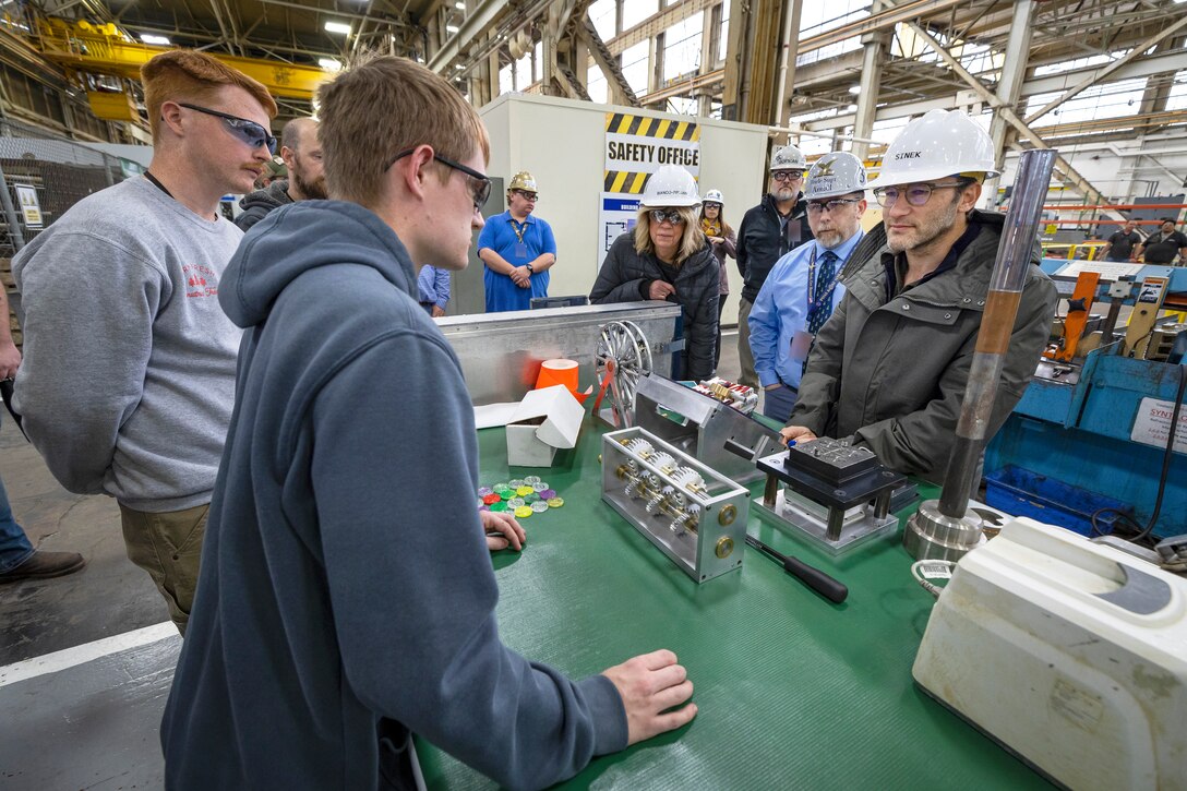 Author Simon Sinek listens to a presentation by Shop 31, Inside Machinist shop, employees on their recent innovations, during a tour of Building 431 Dec. 12, 2022, at Puget Sound Naval Shipyard & Intermediate Maintenance Facility in Bremerton, Washington. (U.S. Navy photo by Scott Hansen)