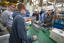 Author Simon Sinek listens to a presentation by Shop 31, Inside Machinist shop, employees on their recent innovations, during a tour of Building 431 Dec. 12, 2022, at Puget Sound Naval Shipyard & Intermediate Maintenance Facility in Bremerton, Washington. (U.S. Navy photo by Scott Hansen)