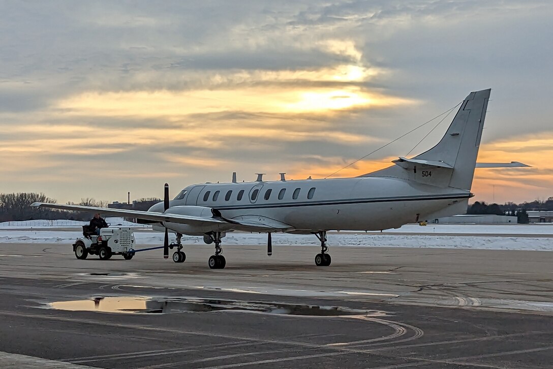 Maintenance specialists for the Wisconsin Air National Guard's RC-26B reconnasance aircraft tow it into an aircraft ramp at Dane County Regional Airport following it's final flight Dec. 28, 2022.