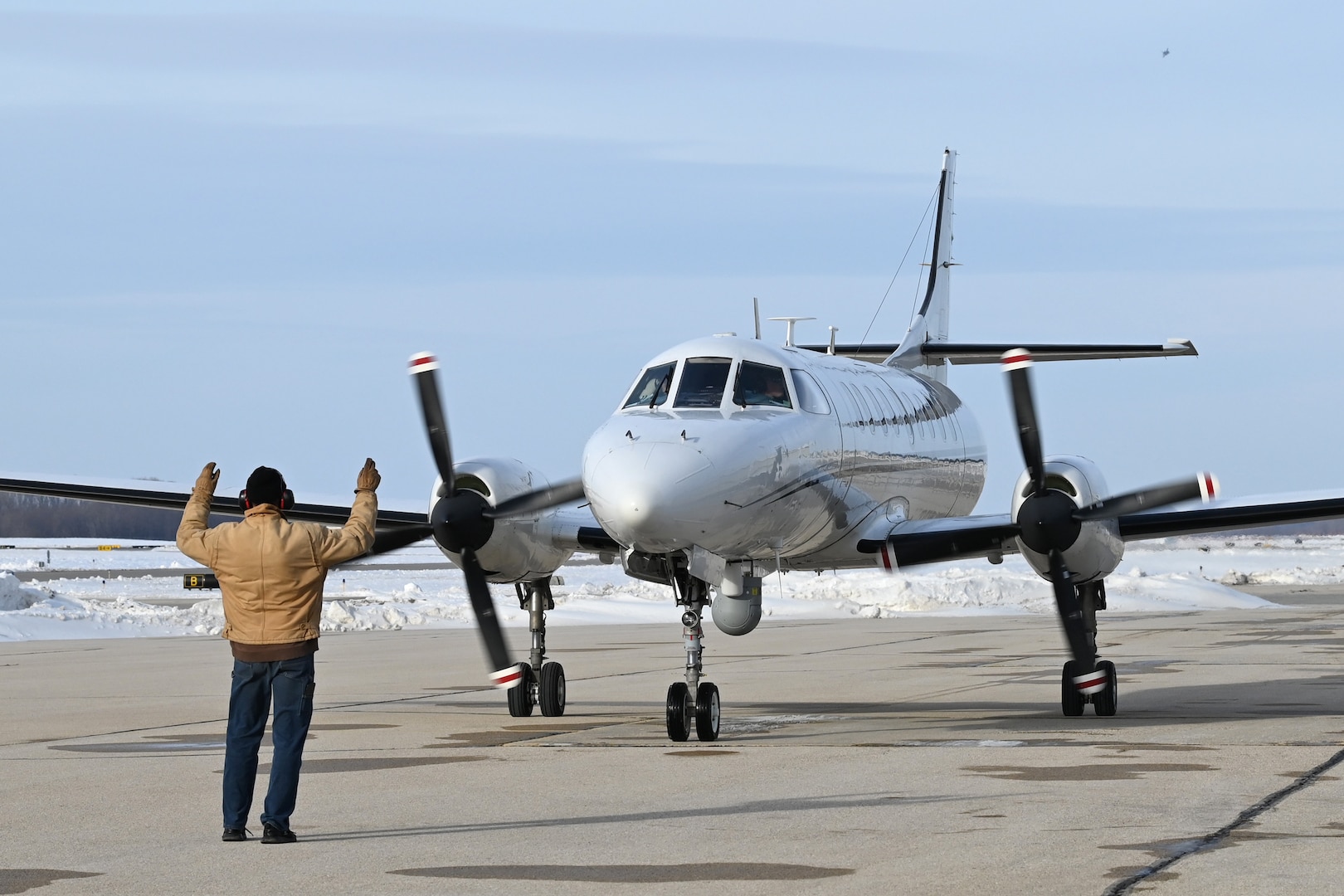 A maintenance specialist for the Wisconsin Air National Guard's RC-26B reconnaissance aircraft marshals it onto an aircraft ramp at Dane County Regional Airport following it's final flight Dec. 28, 2022