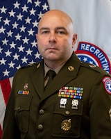 man in u.s. army uniform standing in front of flags.