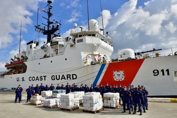 The crew of the Coast Guard Cutter Forward pose with approximately 13,375 pounds of cocaine in Port Everglades, Florida, Dec. 15, 2022. The offload contained an estimated $176 million in cocaine the Coast Guard and its partners intercepted in the international waters of the Caribbean Sea.
