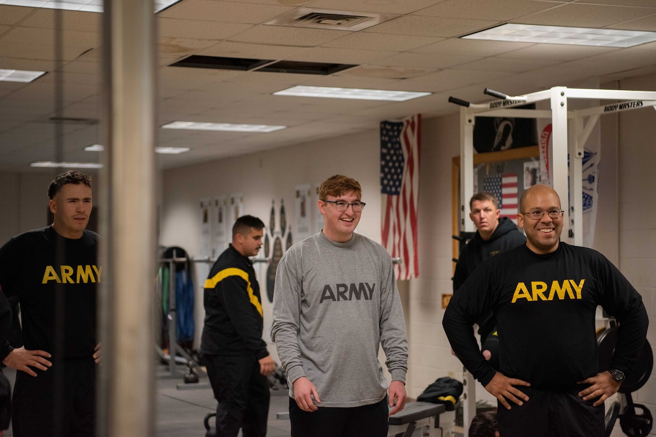 Three men wear t-shirts bearing the word Army, as two other men look on.