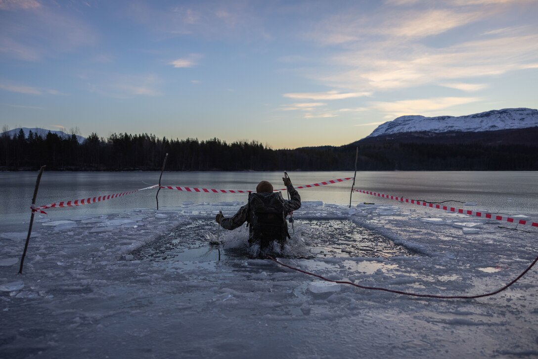 A U.S. Marine with 2d Combat Engineer Battalion, 2d Marine Division, executes an arctic plunge during the NATO Winter Instructor Course (NWIC) in Setermoen, Norway, Nov. 25, 2022. NWIC is a course designed to develop Marines and other service members to be instructors of cold weather survival training in preparation for future deployments. (U.S. Marine Corps photo by Lance Cpl. Averi Rowton)