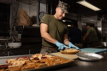 U.S. Marine Corps Cpl. Mason Shea a food service specialist, assigned to 2nd Landing Support Battalion, 2nd Marine Logistics Group, II Marine Expeditionary Force (MEF) and native of Kansas City, Missouri, cuts pie to be served at a Thanksgiving meal aboard the Spearhead-class expeditionary fast transport USNS Trenton (T-EPF 5) in Greece, Nov. 24, 2022. Marines assigned to II MEF, based out of Camp Lejeune, North Carolina, embarked aboard USNS Trenton (T-EPF 5) to improve interoperability while refining the U.S. capability to rapidly deploy forces aboard U.S. Navy expeditionary fast transport vessels. (U.S. Marine Corps photo by Sgt. Scott Jenkins)