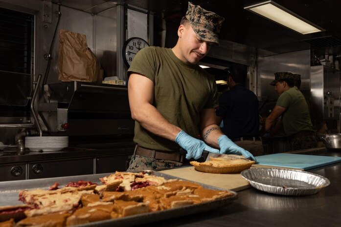 U.S. Marine Corps Cpl. Mason Shea a food service specialist, assigned to 2nd Landing Support Battalion, 2nd Marine Logistics Group, II Marine Expeditionary Force (MEF) and native of Kansas City, Missouri, cuts pie to be served at a Thanksgiving meal aboard the Spearhead-class expeditionary fast transport USNS Trenton (T-EPF 5) in Greece, Nov. 24, 2022. Marines assigned to II MEF, based out of Camp Lejeune, North Carolina, embarked aboard USNS Trenton (T-EPF 5) to improve interoperability while refining the U.S. capability to rapidly deploy forces aboard U.S. Navy expeditionary fast transport vessels. (U.S. Marine Corps photo by Sgt. Scott Jenkins)