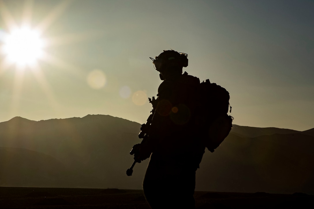 A US Marine in silhouette against the desert  mountains.
