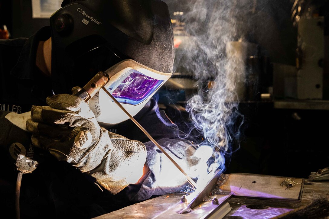 A sailor welds a bracket.