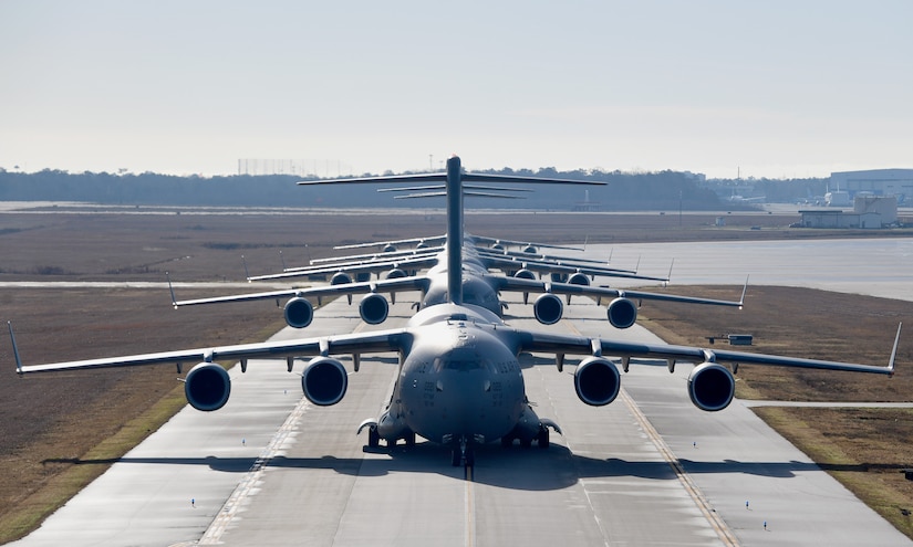 Several aircraft wait to take off on a runway.