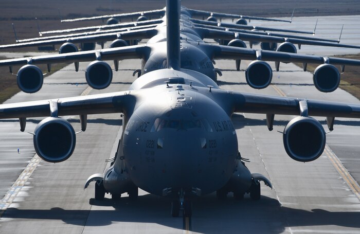 Several aircraft wait to take off on a runway.