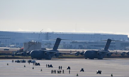 Several aircraft wait to take off on a runway.