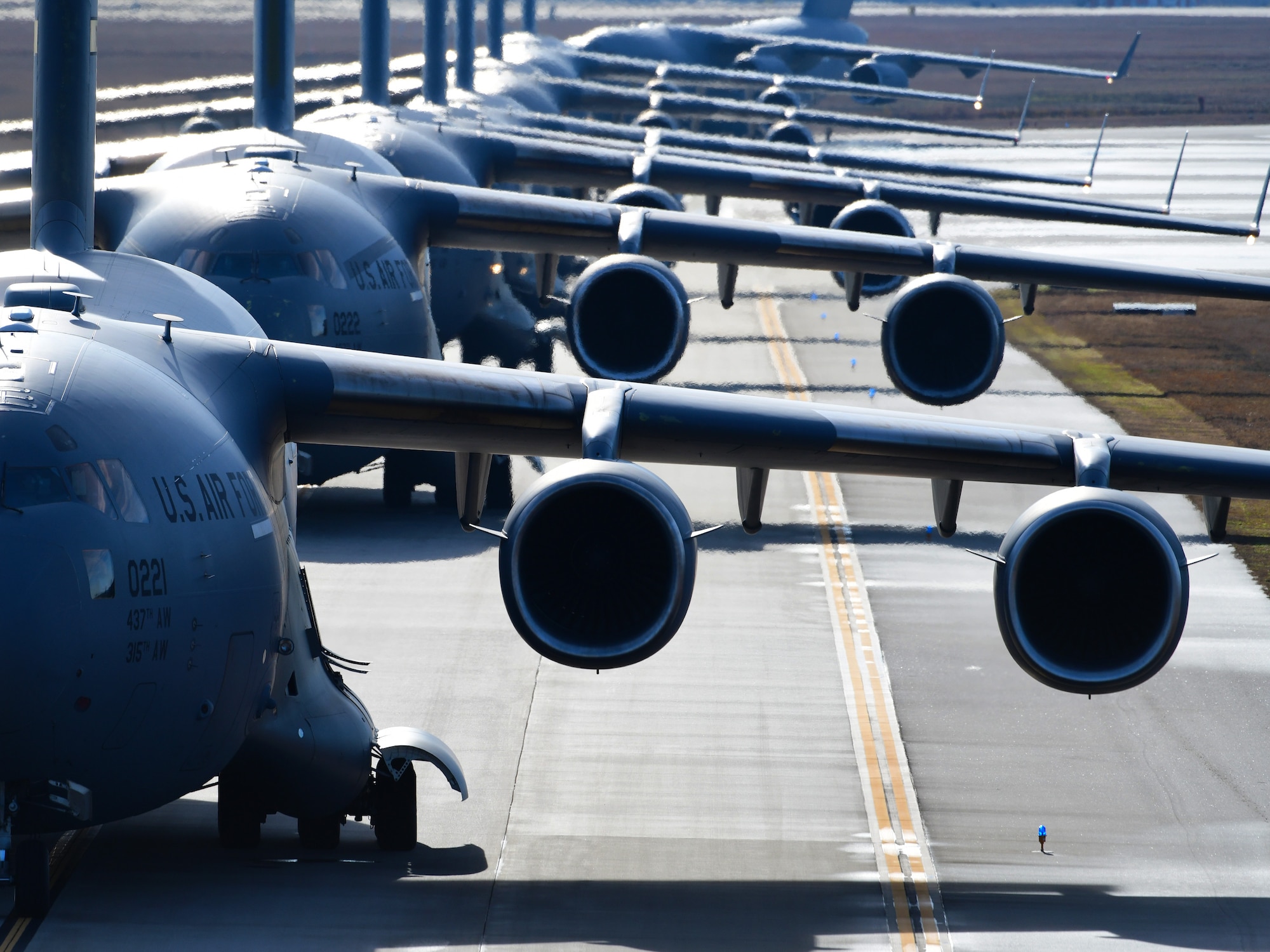 Several aircraft wait to take off on a runway.