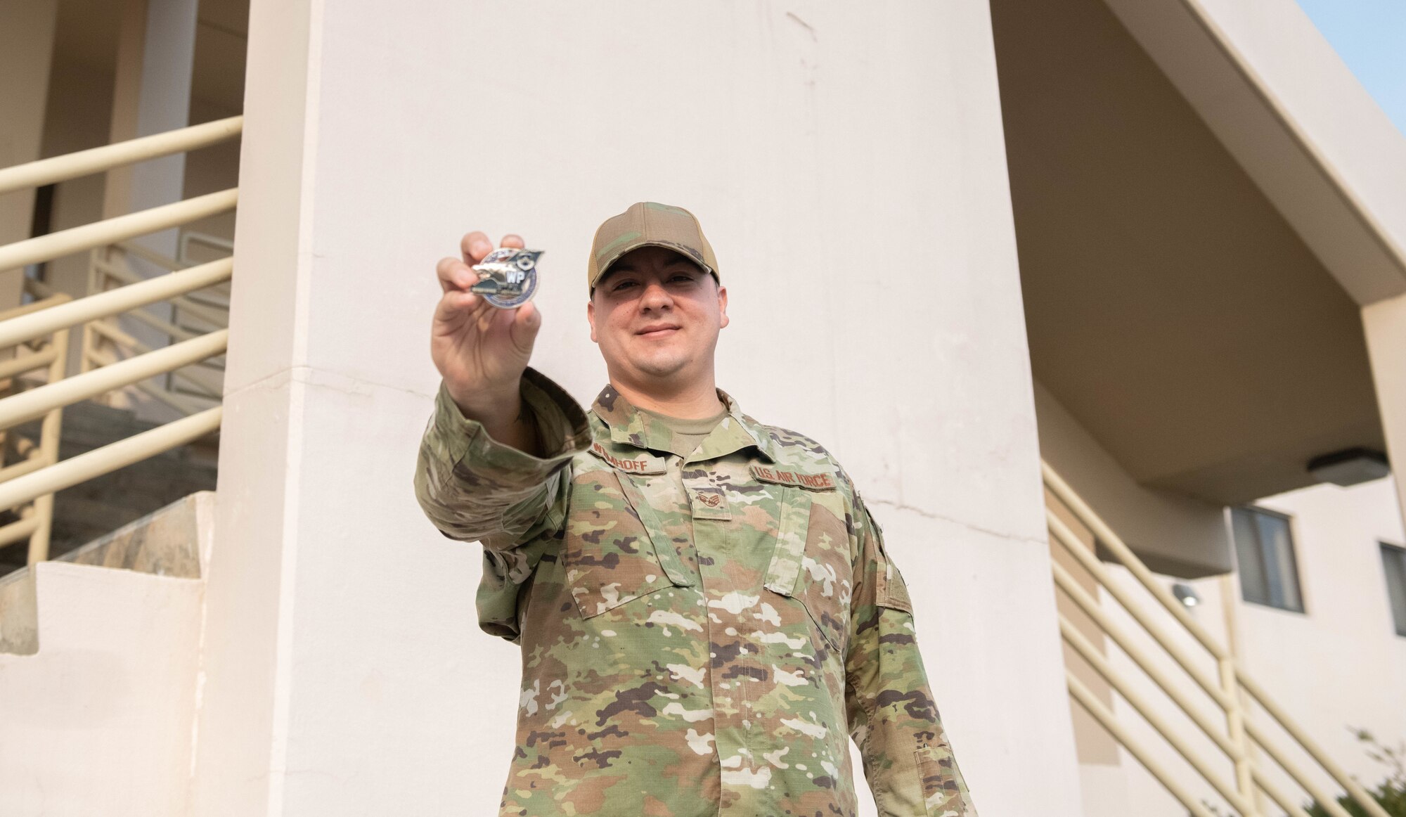 Man in uniform holds up a challenge coin