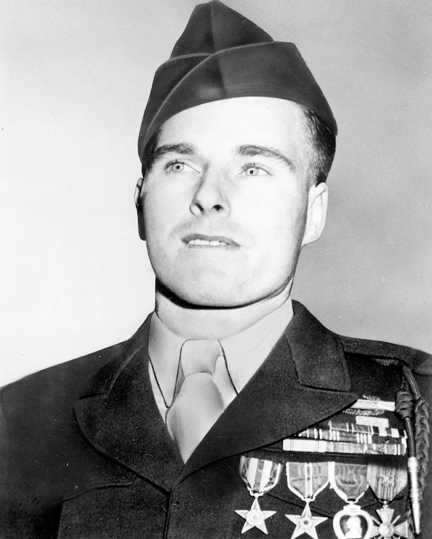 A man wearing several decorations on his lapel poses for a photo.