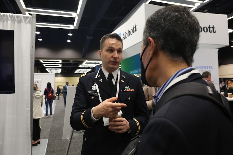 Maj. Thomas Cotrone, Armed Forces Research Institute of Medical Sciences, Department of Virology researcher, talks with an attendee during the American Society of Tropical Medicine and Hygiene 71st Annual Meeting, Oct. 31.
