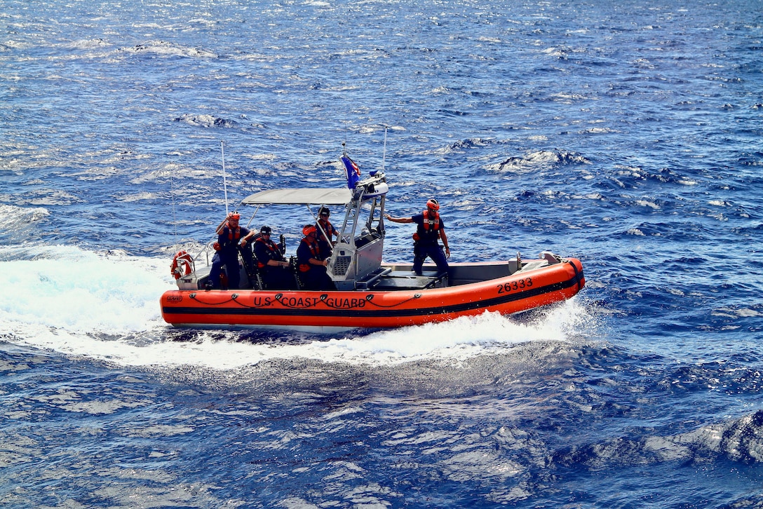 Coast Guardsmen transit a body of water in a small rubber boat.