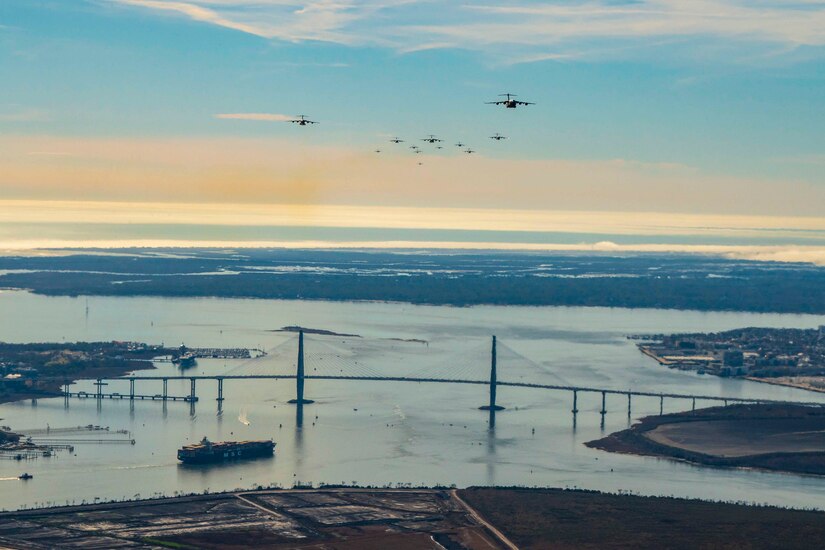 Aircraft fly in formation over a bridge.
