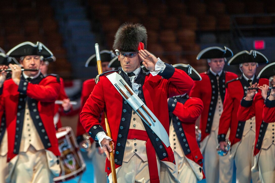 Soldiers assigned to the Old Guard play instruments and salute during a retirement ceremony.