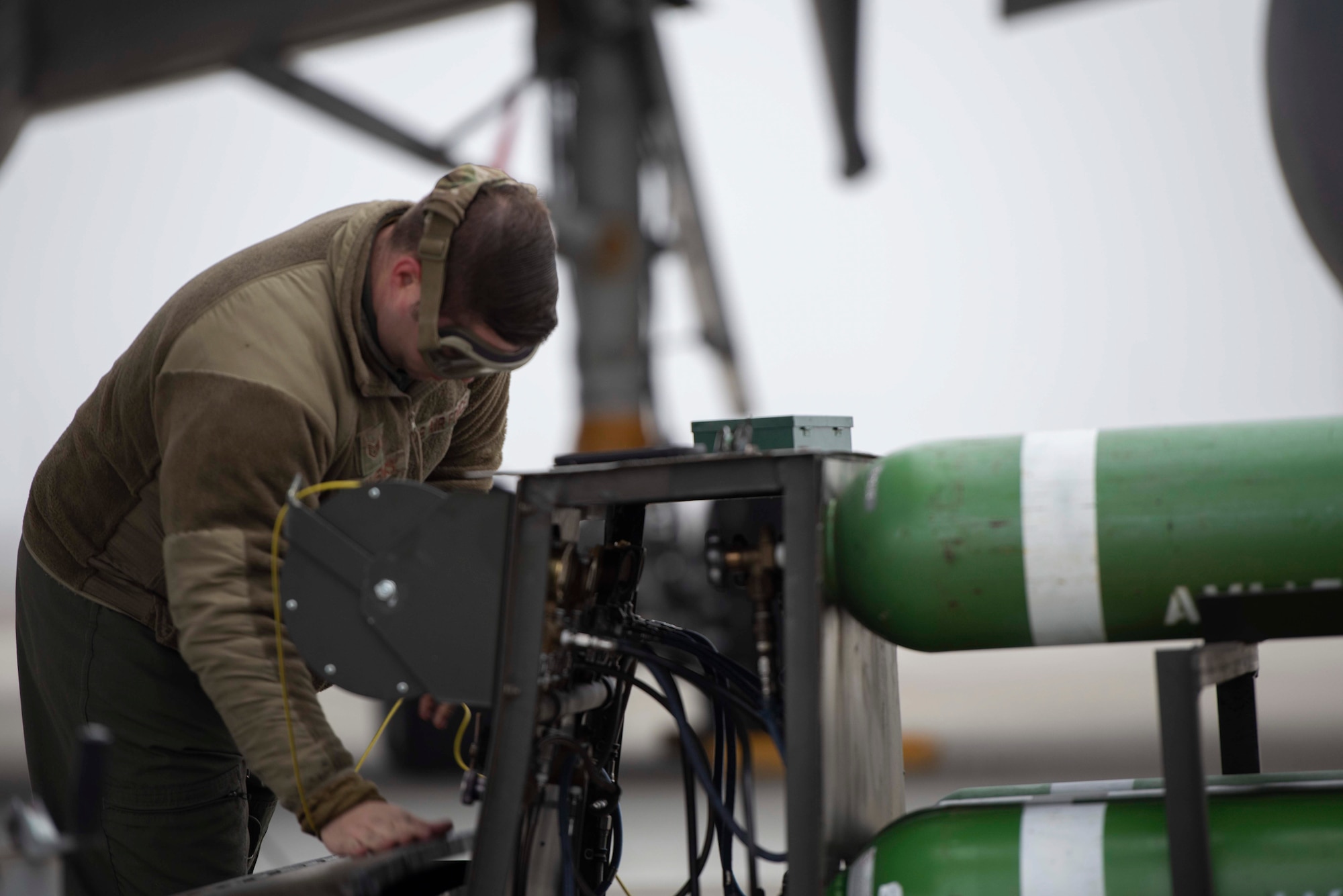 A military member uses a large green tank.