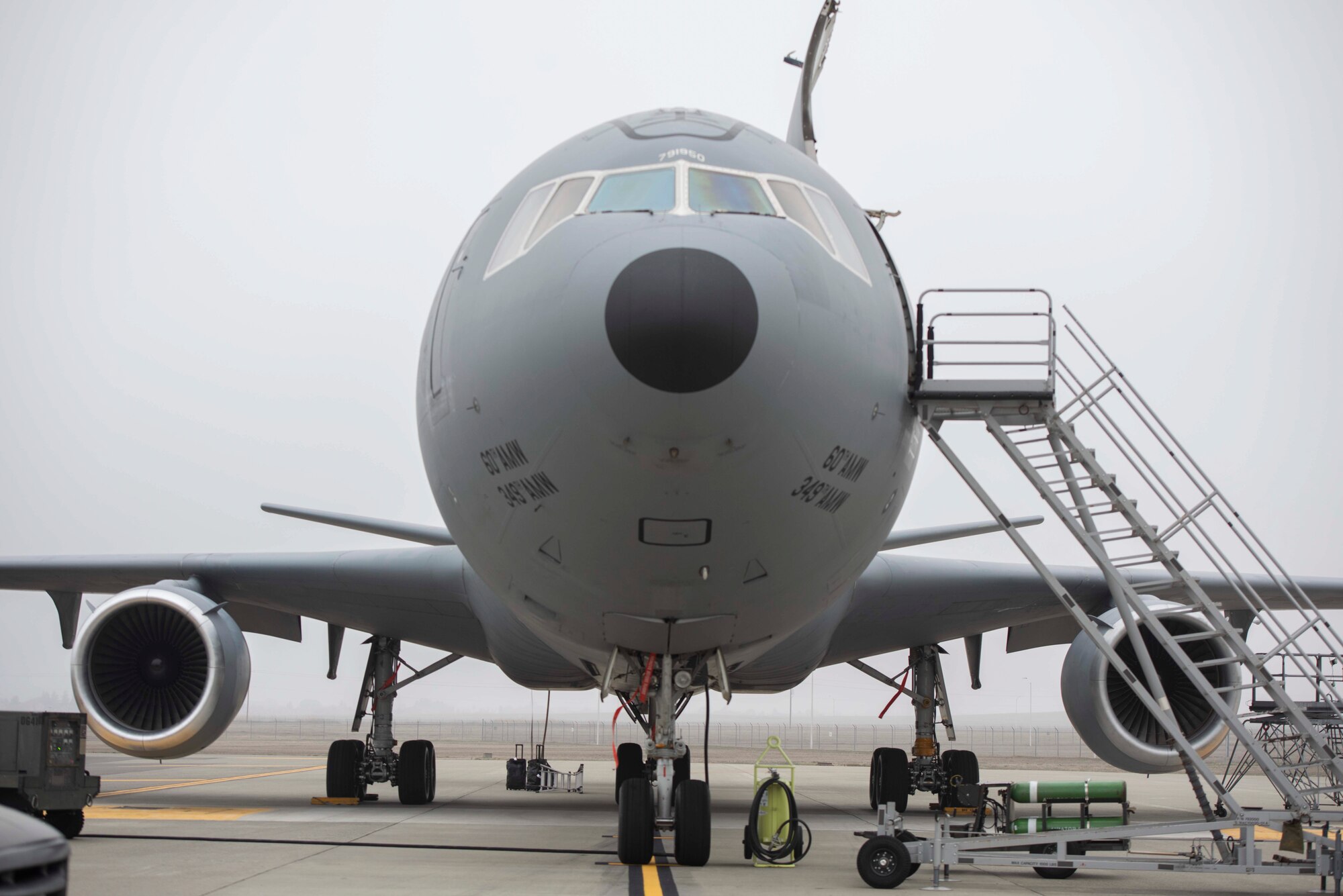 A large military aircraft sits on the flight line under an overcast sky.