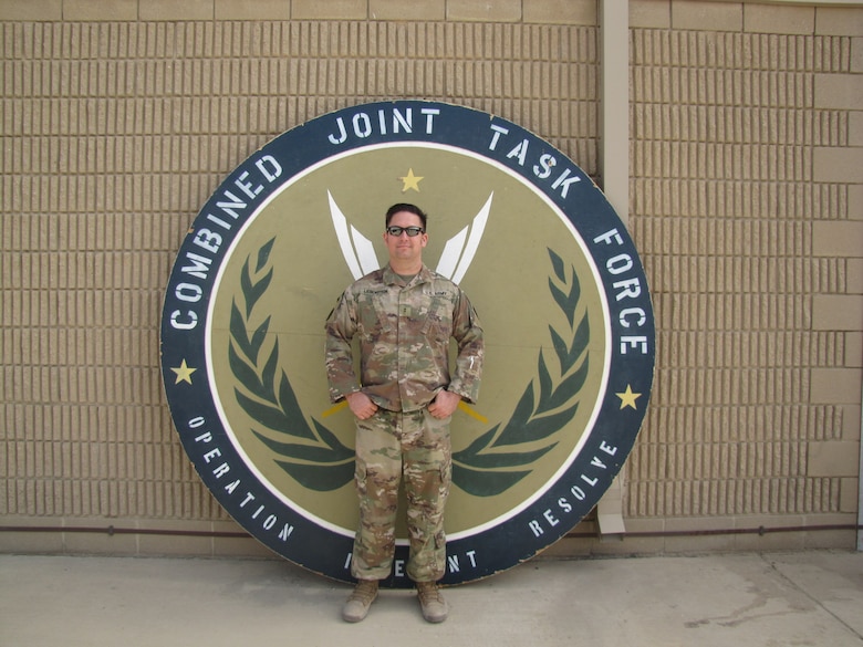 Chief Warrant Officer 2 Derik Liebenstein stands in front of a U.S. Army building in a U.S. Army uniform.