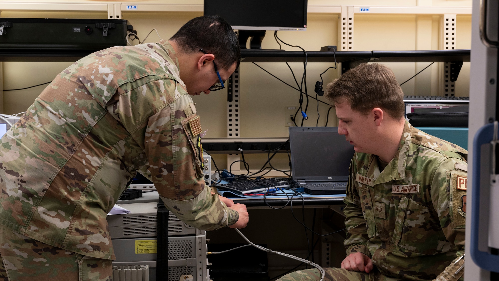 U.S. Air Force Senior Airman Joshua Pouncey, 49th Component Maintenance Squadron physical dimensional technician, left, trains U.S. Air Force Senior Airman Walker, 49th CMS physical dimensional technician, on how to use a Joint Services Electronic Combat Systems Tester at Holloman Air Force Base, New Mexico, Jan. 6, 2023. Airmen from the precision measurement equipment laboratory flight are responsible for calibrating the equipment used by aircraft maintainers to ensure it’s in working order and set to the exact measurements. (U.S. Air Force photo by Airman 1st Class Nicholas Paczkowski)