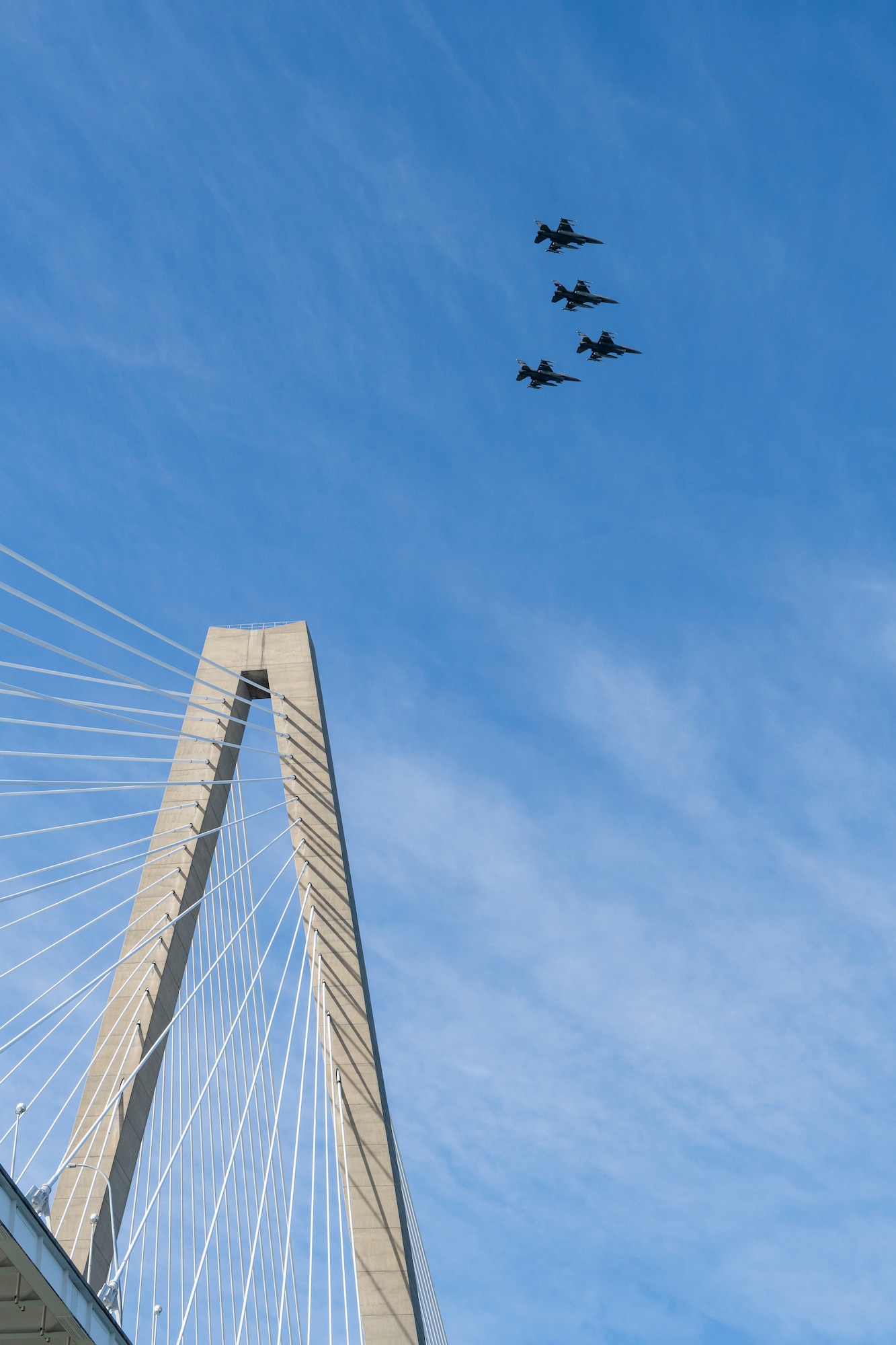 A photo of four F-16s flying over a bridge.