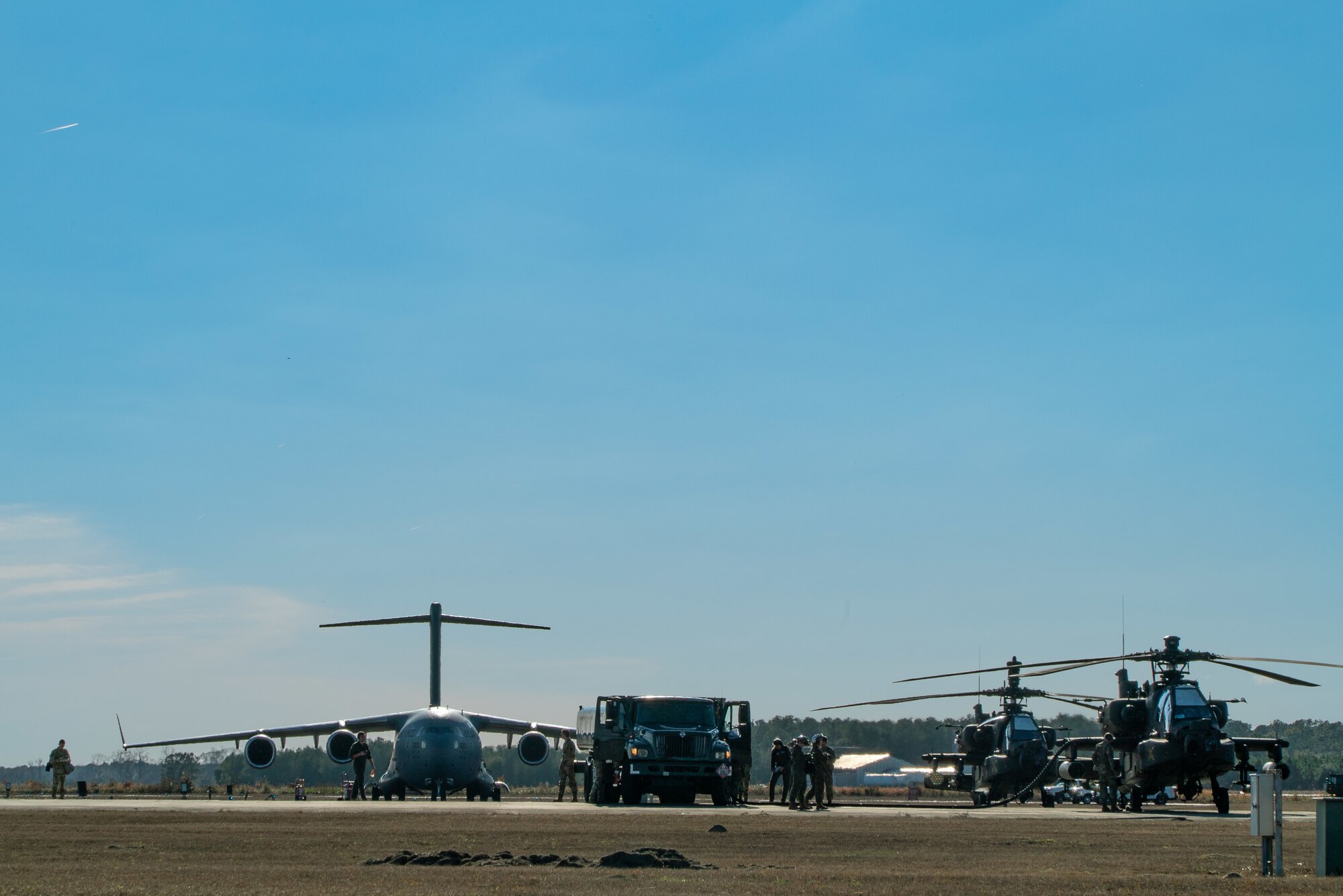 A photo of a C-17, refueling truck and two Apache helicopters