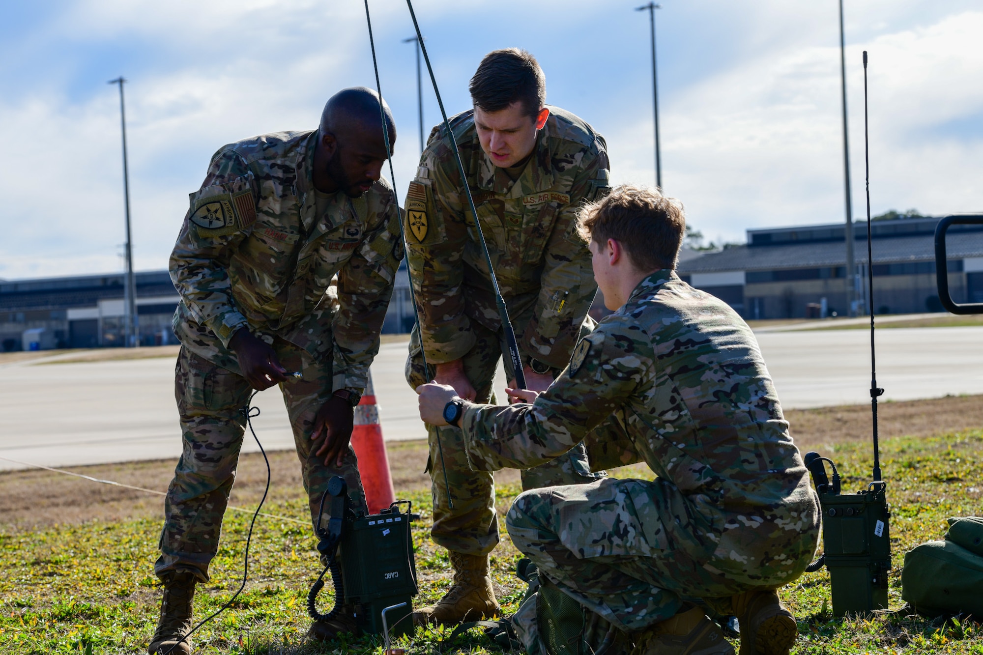 A photo of three Airmen operate radio equipment.