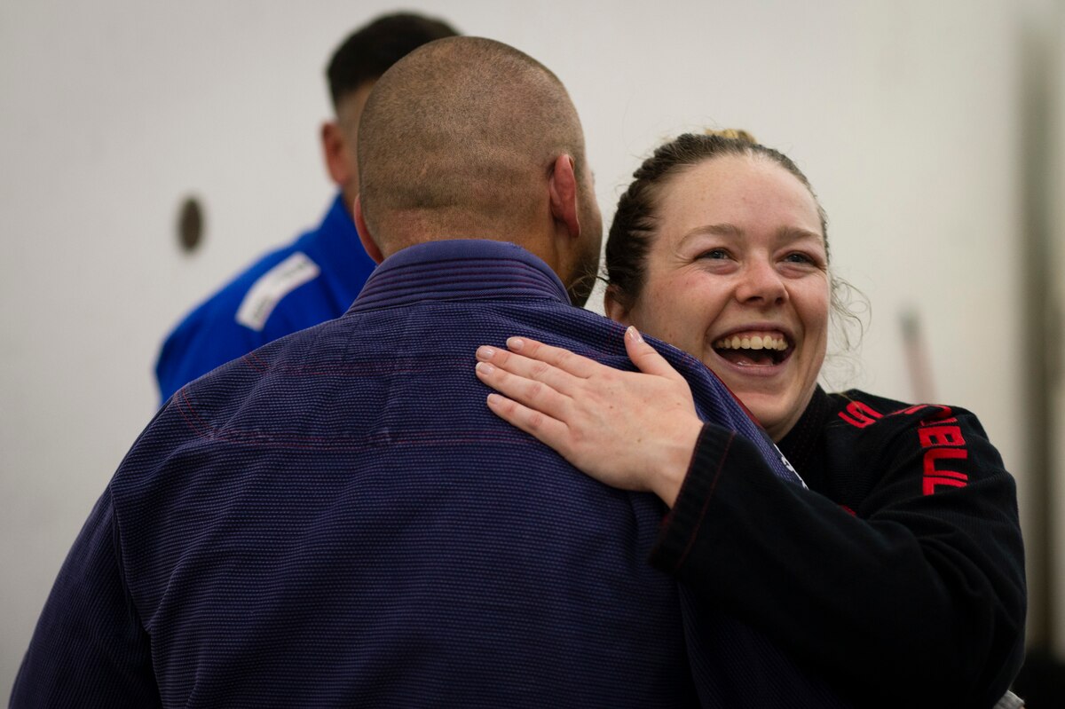 From right, Senior Airman Kaylee Tutt, 386th Expeditionary Security Forces Squadron pass and ID clerk, hugs Tech. Sgt. Justin Leon Guerrero, 386th Expeditionary Security Forces Squadron military working dog trainer and Jiu-Jitsu team coach, after receiving a stripe on her Jiu-Jitsu belt during practice at Ali Al Salem Air Base, Kuwait, Dec. 30, 2022. The stripes on each person's belt symbolize the commitment, dedication and knowledge gained while practicing Jiu-Jitsu. (U.S. Air Force photo by Staff Sgt. Dalton Williams)