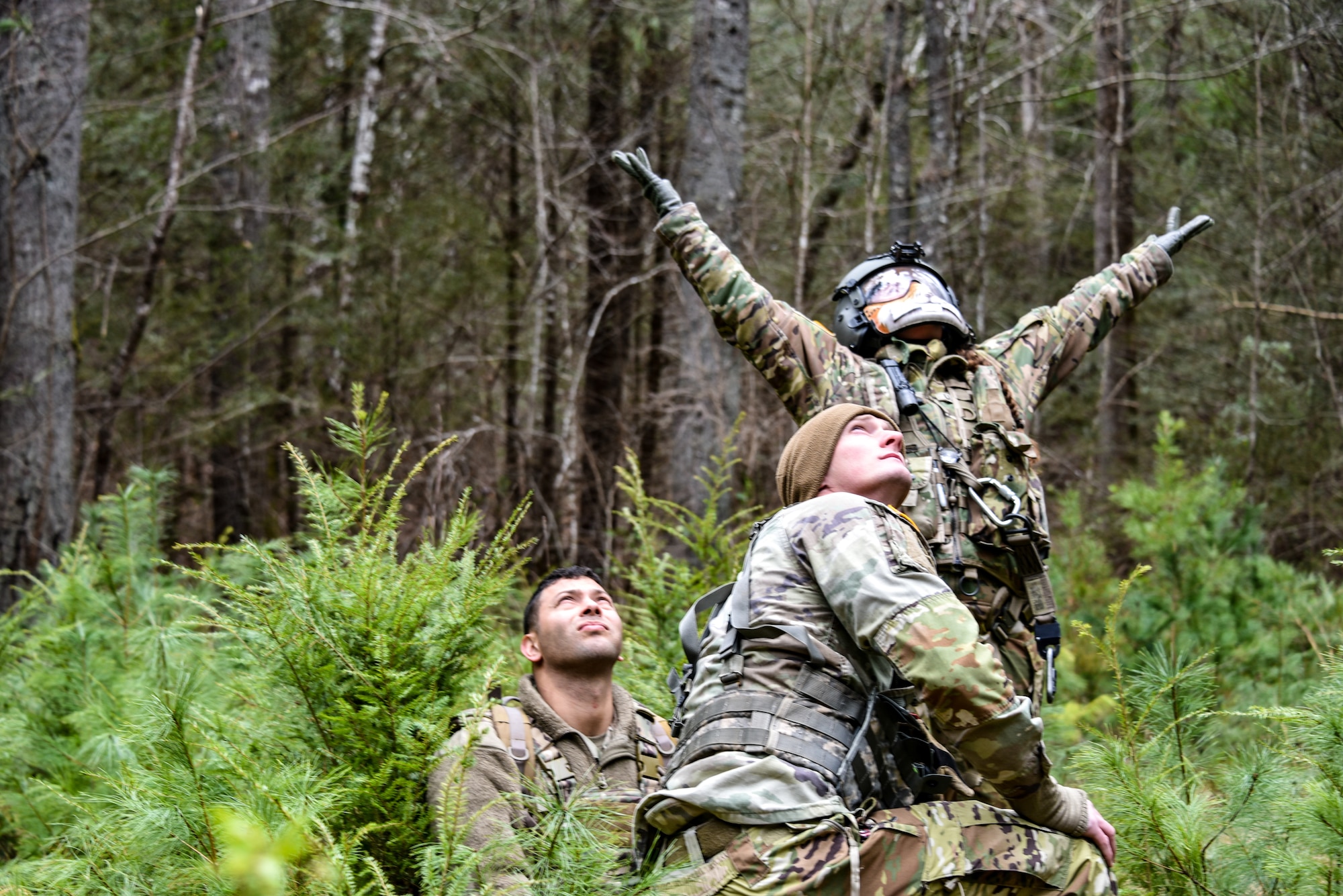 three soldiers wait in a forest clearing for helicopter lift