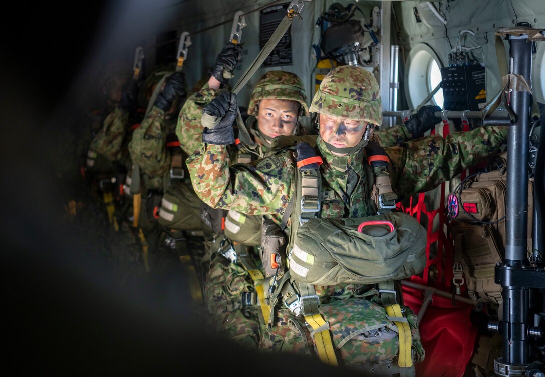 Paratroopers stand under the static line on a C-130J