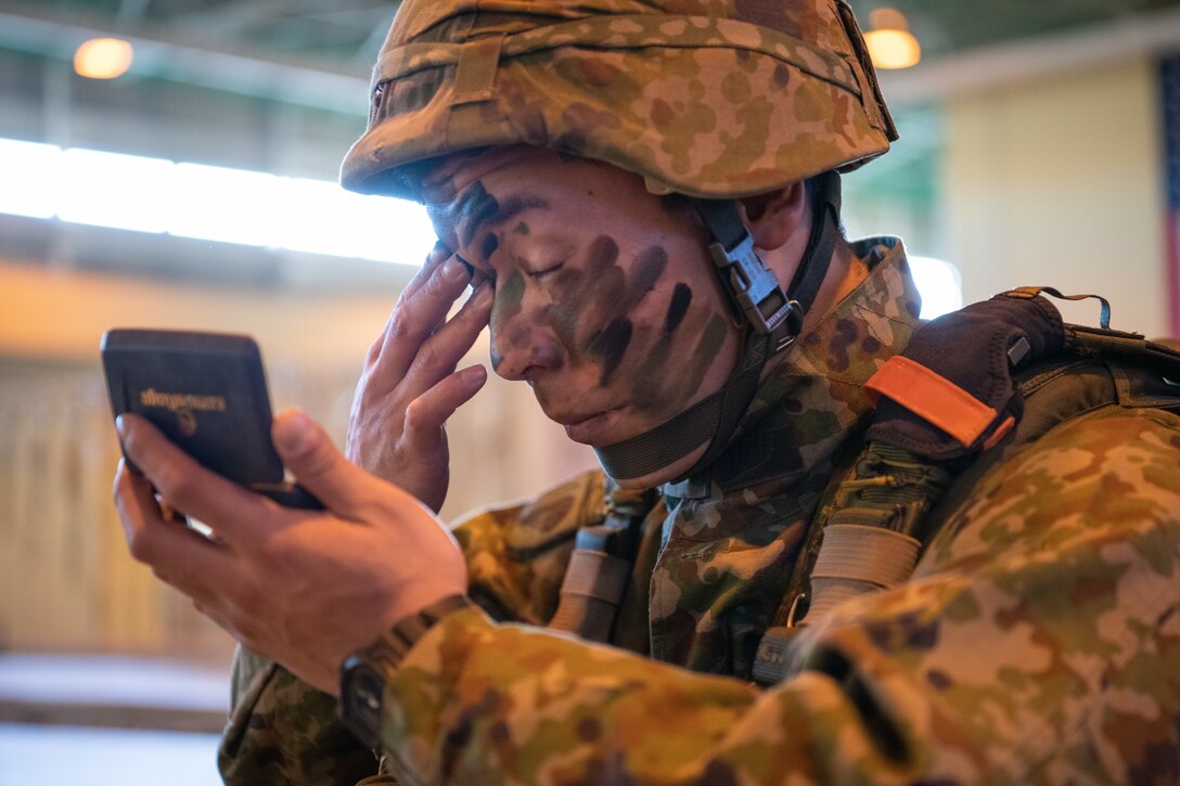 A paratrooper applies paint to his face