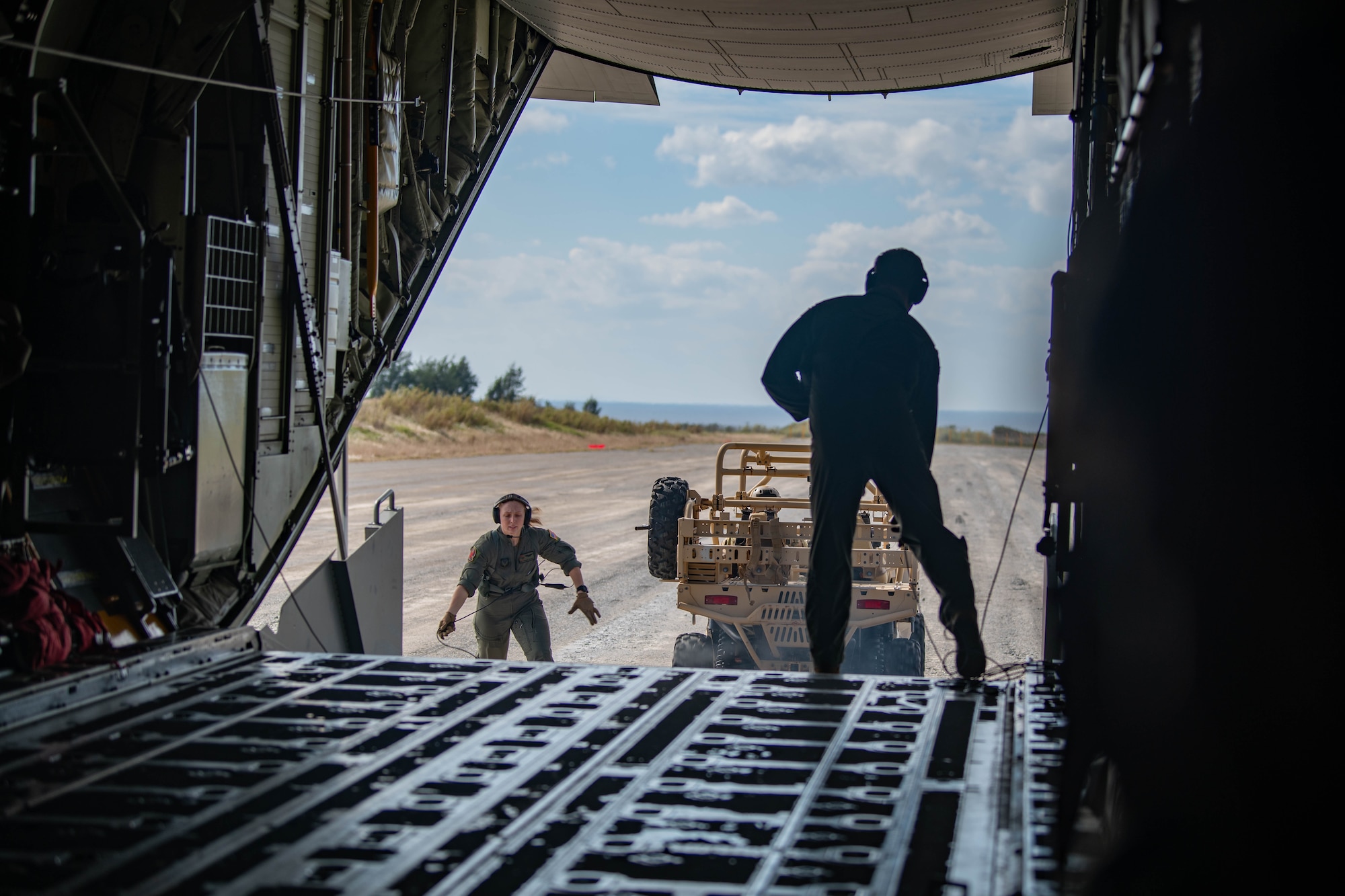 Two Airmen unload a vehicle off of an aircraft.