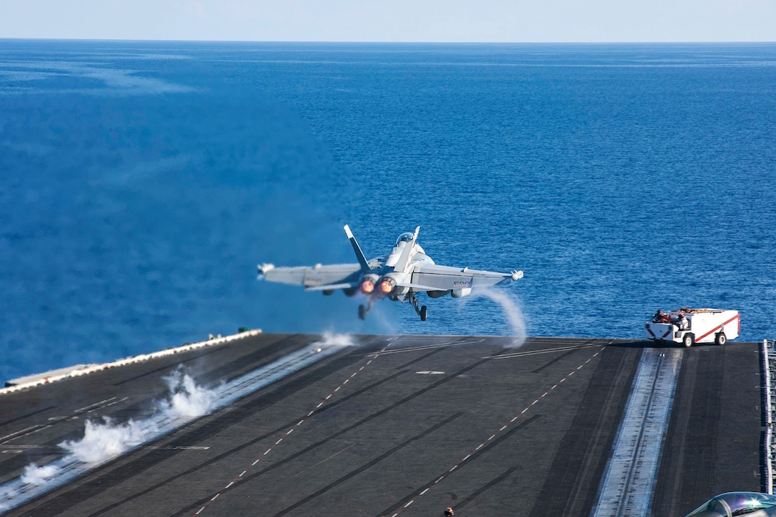 A plane launches from the deck of an aircraft carrier at sea.