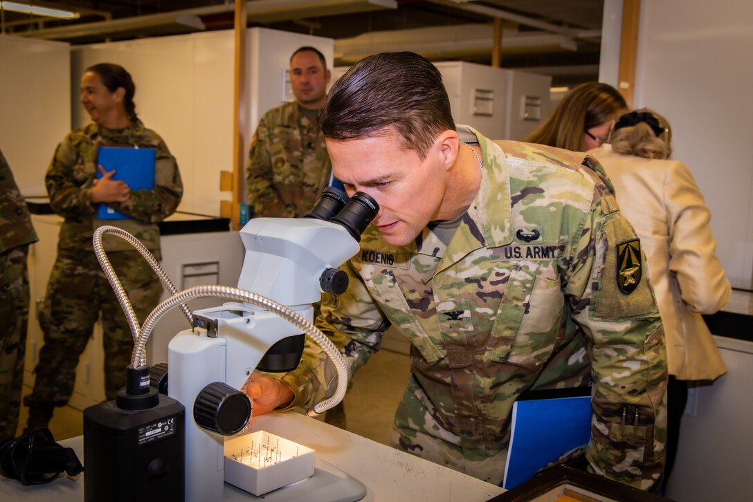 Col. Chad Koenig looks through a microscope.