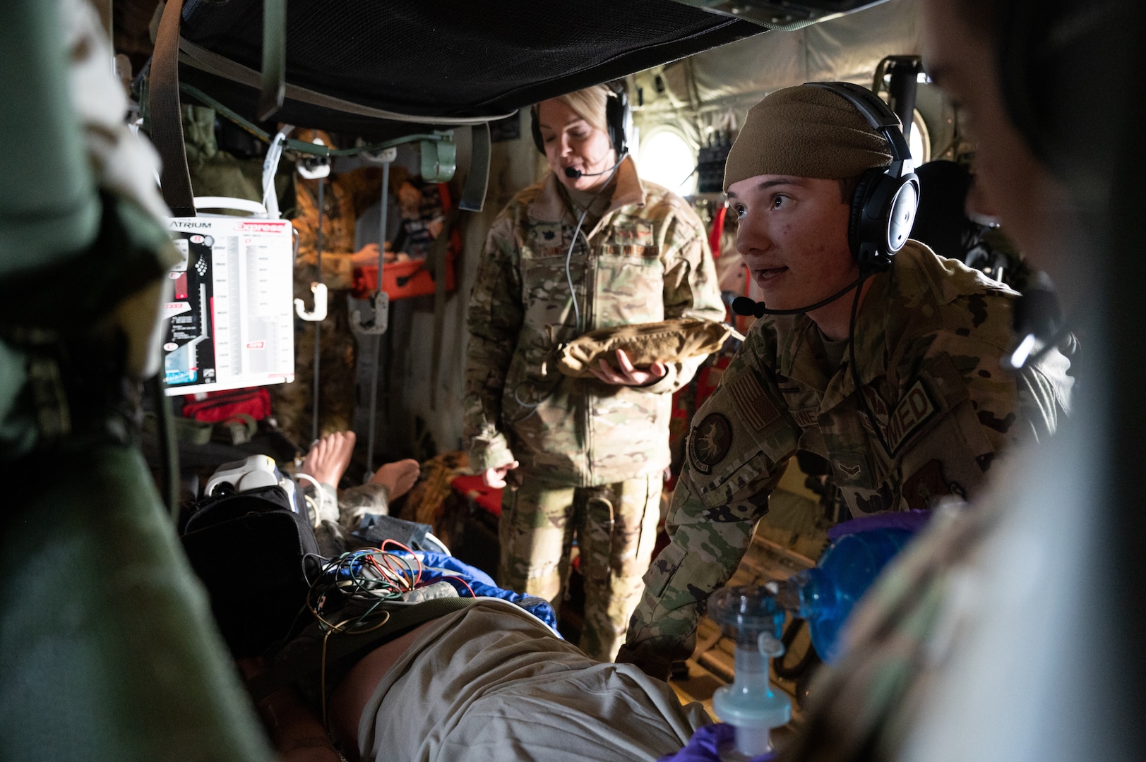 From left, U.S. Air Force Lt. Col. Trina Young, a flight nurse assigned to the 167th Aeromedical Evacuation Squadron based at McLaughlin Air National Guard Base, Charleston, West Virginia, holds medical equipment, while flight medics Airman 1st Class Caleb Wynne and Airman 1st Class Haleigh Romage attempt to resuscitate a simulated dying patient during a medical evacuation exercise aboard a C-130J, Dec. 20, 2022. The 167th AES conducted in-flight emergency medical simulation training to maintain currency and hone their medical skills for real-world missions. (U.S. Air National Guard photo by Airman 1st Class Kaden Salmons)