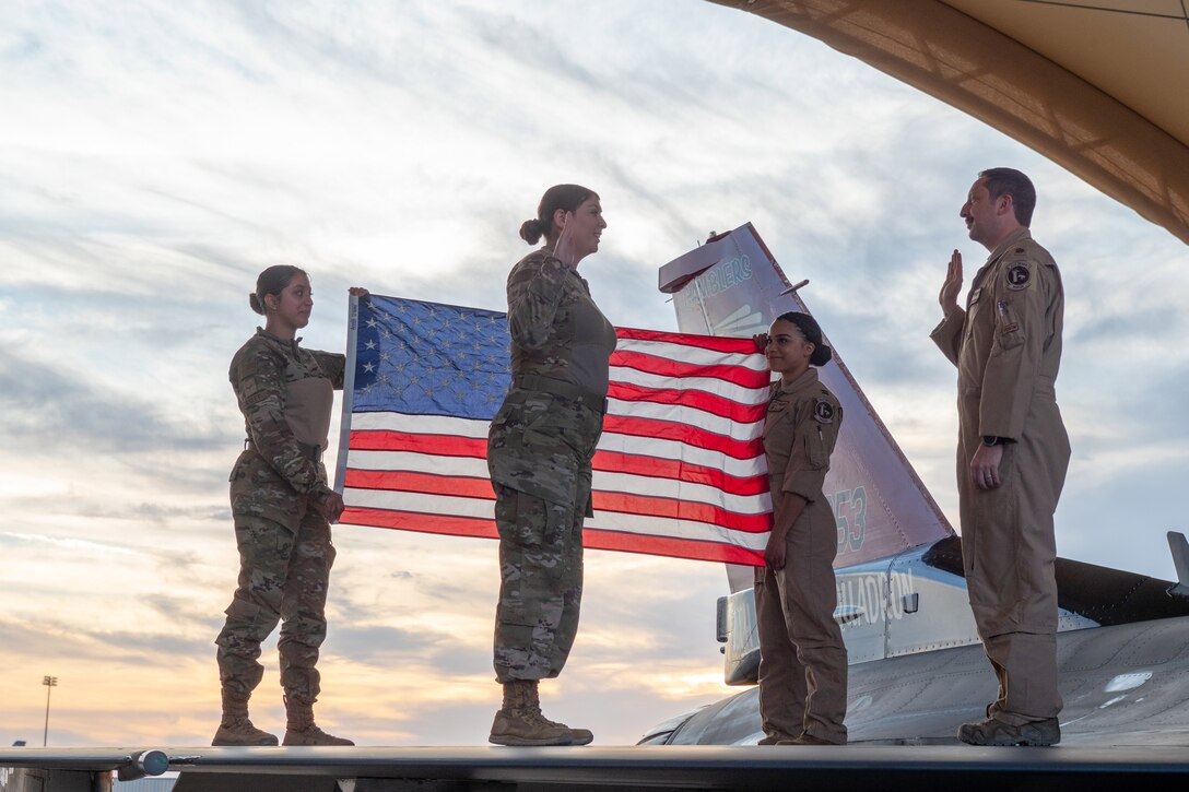 Four service members stand on the wing of a military aircraft as one reenlists in the military.