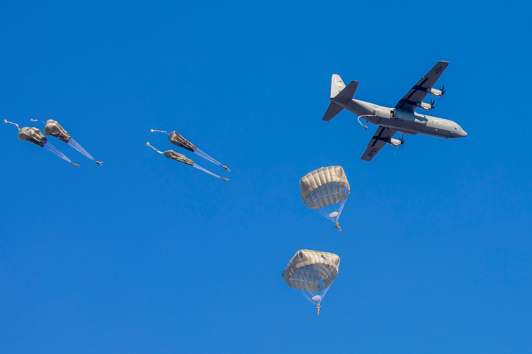 Soldiers free fall with parachutes after jumping from an aircraft.