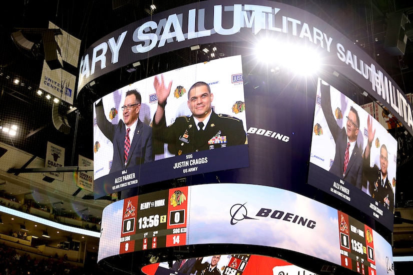 Retired Air Force veteran Alex Parker (left) and Staff Sgt. Justin Craggs, Mobilization Non-Commissioned Officer, 85th U.S. Army Reserve Support Command, are pictured on the United Center jumbotron as hockey fans stand on their feet cheering during a military salute at a Chicago Blackhawks military appreciation night game, January 6, 2023, at the United Center.