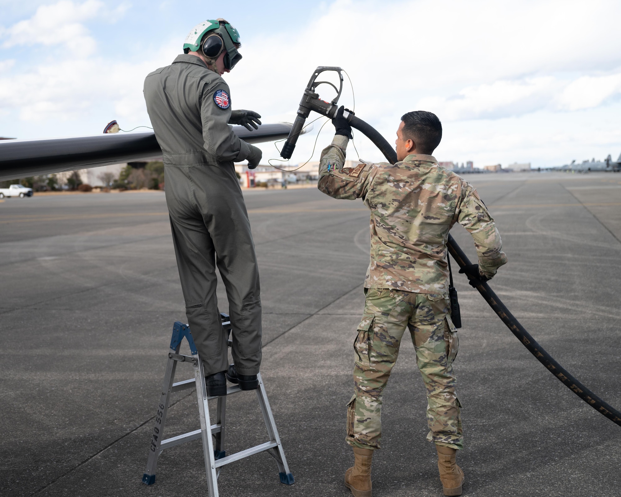 U.S. Air Force Airman 1st Class Juan Ortiz, hands a pilot a fuel pump at Yokota Air Base