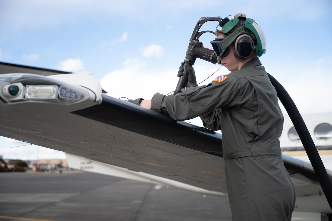 A U.S. Navy pilot from Naval Air Facility Misawa pumps fuel into a C-12J Huron at Yokota Air Base