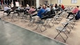 Photo of a group of people in a large conference area, seated in chairs during a training presentation