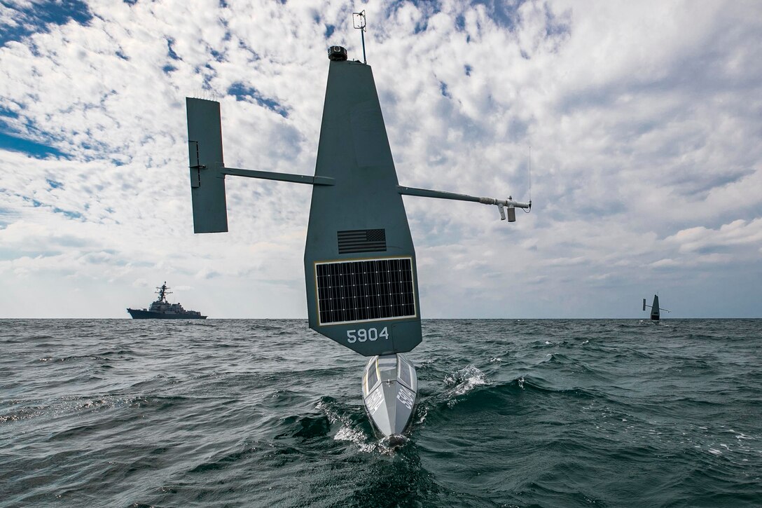 Three military vessels operate in the water.