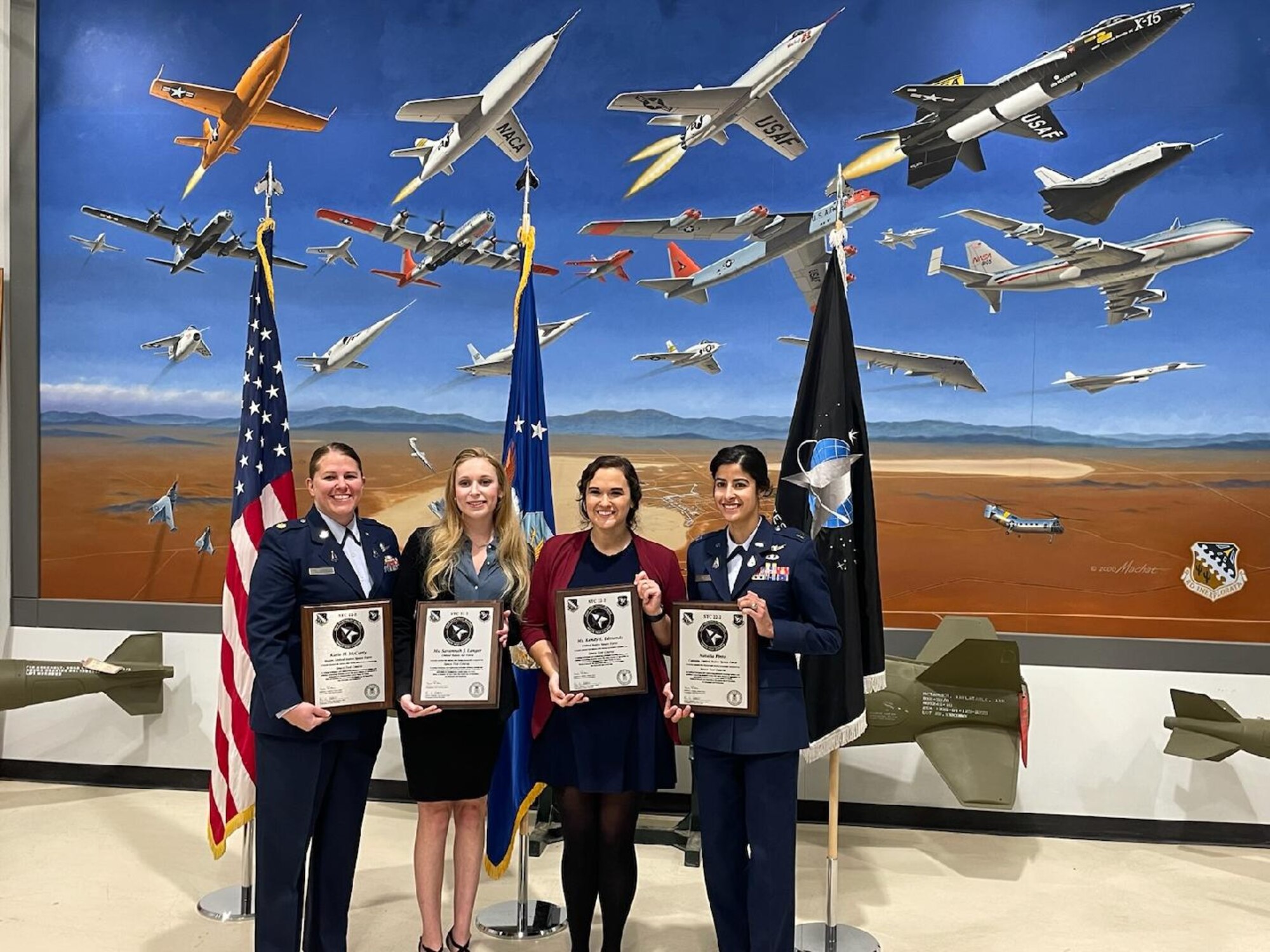 Savannah Langer, second from left, and three of her 412th Test Wing U.S. Air Force Test Pilot School Space Test Course classmates stand and pose for a photo with their plaques following graduation.