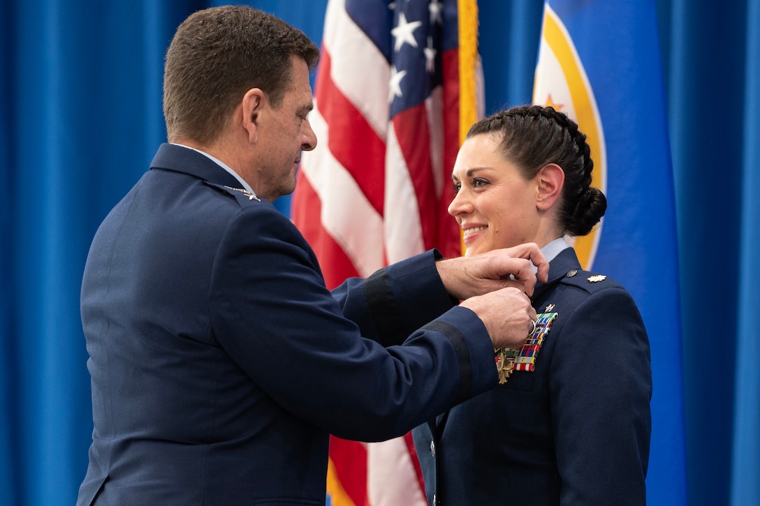 An airman places a medal on another airman's uniform.