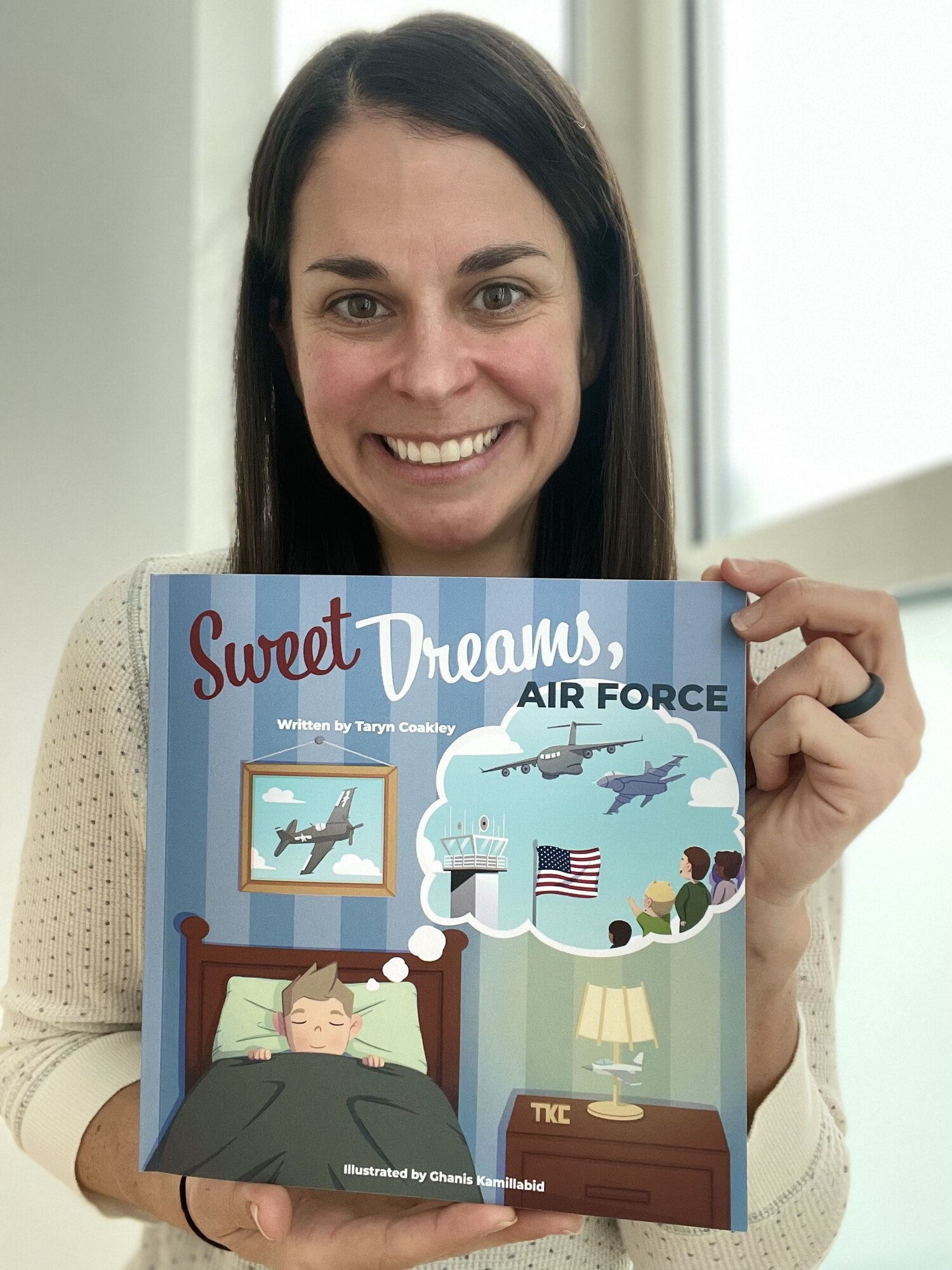 Taryn Coakley, 726th Air Mobility Squadron Key Spouse Mentor, presents a copy of her newly self-published children’s book "Sweet Dreams, Air Force" at Spangdahlem Air Base, Germany, Dec. 22, 2022.