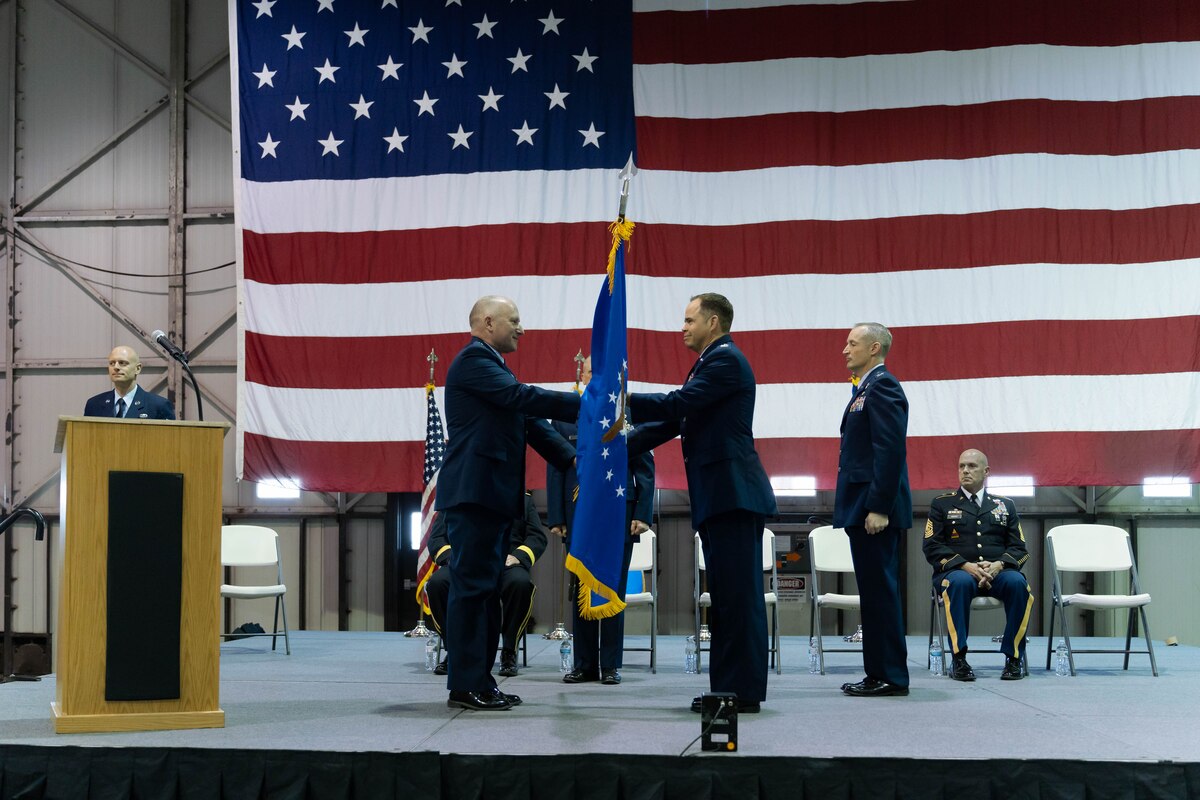 U.S. Air Force Col. Brandon Eskam, right, incoming 114th Fighter Wing base commander, Joe Foss Field, center, receives the 114th Fighter Wing guidon from Brig. Gen. Greg Lair, left, South Dakota Assistant Adjutant General for Air, left, during a change of command ceremony, Sioux Falls, South Dakota, Jan. 8, 2023